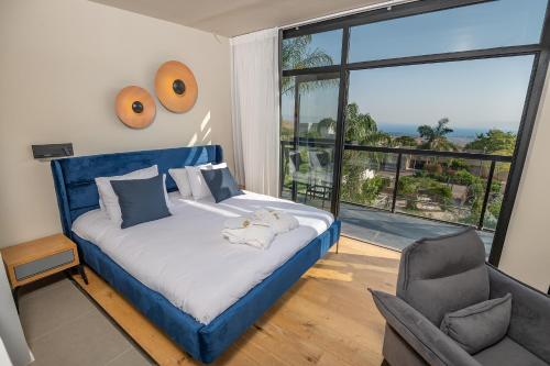 a bedroom with a blue bed and a chair and a window at yoga Lake view in Had Nes