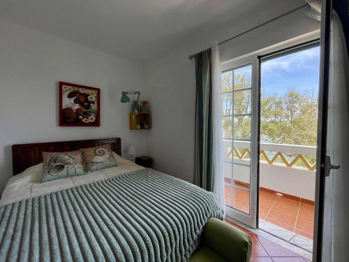 a bedroom with a bed and a large window at Milfontes Villa in Vila Nova de Milfontes