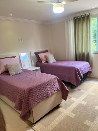 a bedroom with two beds with purple comforters at Apartamento Charmoso e Tranquilo para sua Estadia in Vargem Alta
