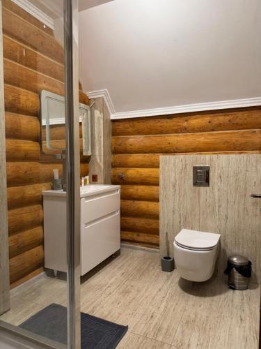 a bathroom with a white toilet and wooden walls at PRINCE Villa in Shaian