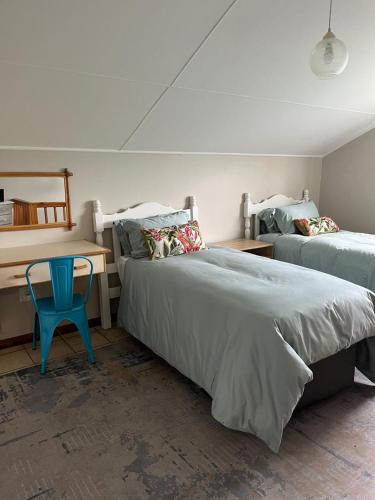 a bedroom with two beds and a desk and a blue chair at River & Salt at Stilbaai in Stilbaai-Oos