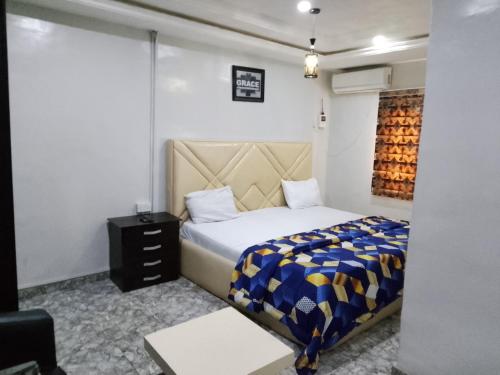 a bedroom with a bed with a blue and yellow blanket at Kembod hotel & suite in Ikeja
