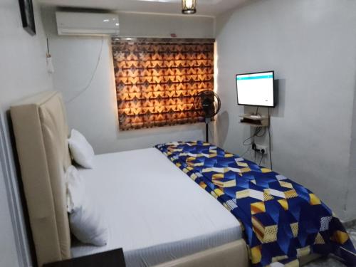 a small bedroom with a bed and a television at Kembod hotel & suite in Ikeja