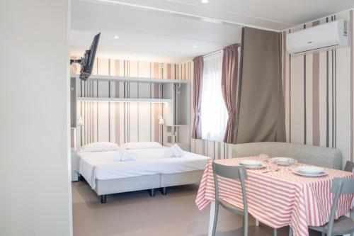 a bedroom with a bed and a table and chairs at Cesenatico Camping Village in Cesenatico