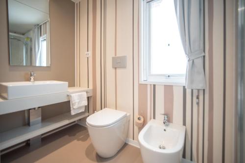 a bathroom with a toilet and a sink and a window at Cesenatico Camping Village in Cesenatico