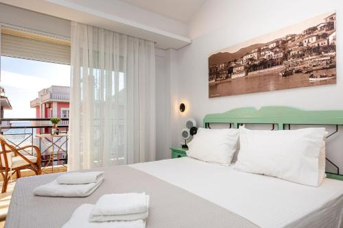 a white bedroom with a bed and a balcony at Limenaria Beach in Limenaria