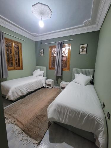 two beds in a room with green walls at Villa RAHA villa entière in El Aggada