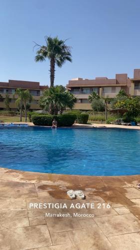 a person in a swimming pool with a palm tree at Prestigia Marrakech in Inezgane