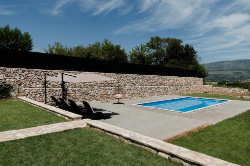 a pool with chairs and an umbrella in a yard at Lastva Nature Retreat in Mostar