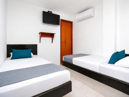 two beds in a room with a tv on the wall at Hotel Masinda in Cartagena de Indias