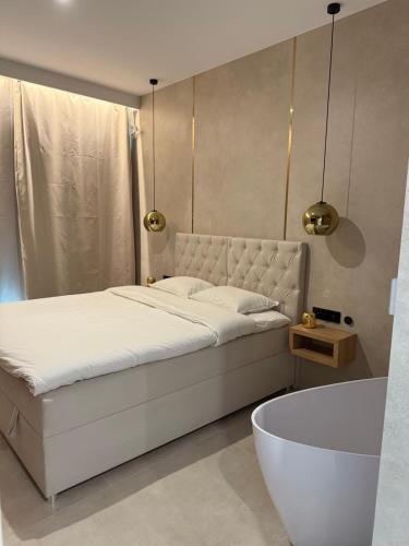 a bedroom with a white bed and a bath tub at Apartament - VIDOK 109 in Olsztyn