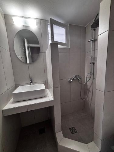 a bathroom with a sink and a mirror and a shower at Kapetan Sorokos Studios 2 in Koufonisia