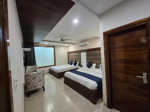a hotel room with two beds and a chair at Hotel Clover in Zirakpur