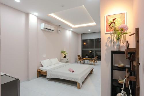 a white room with a bed and a table at Bống's Homestay and Cafe in Ho Chi Minh City
