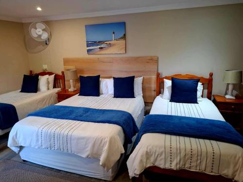 a bedroom with two beds with blue and white sheets at Rest-a-While Guest House - Pretoria in Pretoria