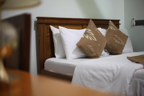 a bed with white pillows and brown pillows at G Villa Executive Hotel in Dodoma