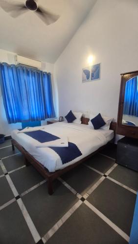 a bedroom with a large bed with blue curtains at Secret kitchen rooms in Candolim