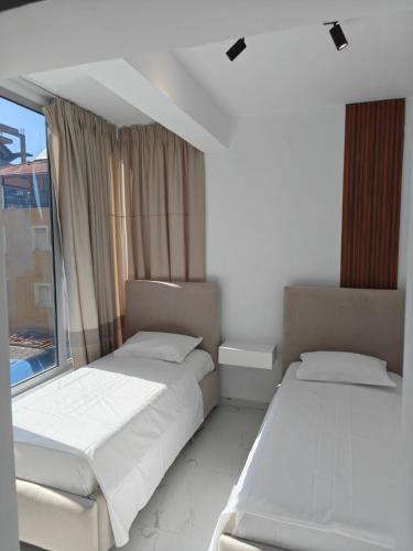 two beds in a room with a window at Hotel Elisabet in Sarandë