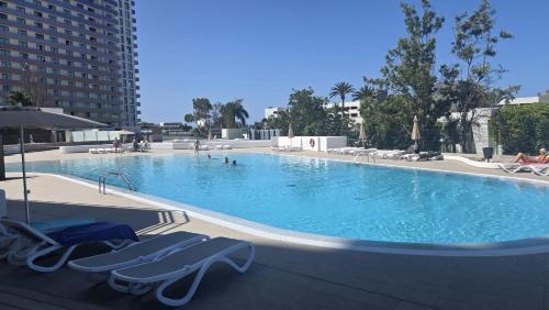 a large swimming pool with lounge chairs in a building at Paraiso Studio in Playa Paraiso