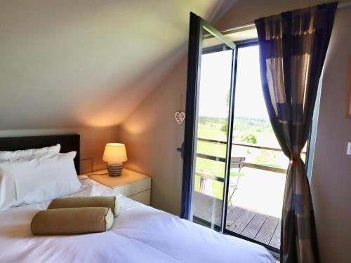 a bedroom with a bed and a window with a balcony at Cocoon in Houffalize