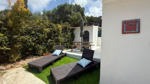 a patio with two chairs and a table on grass at Murches' House in Alcabideche