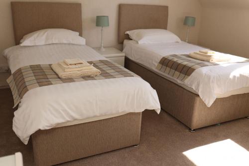 two beds in a bedroom with towels on them at Eastwood Cottage in Turriff