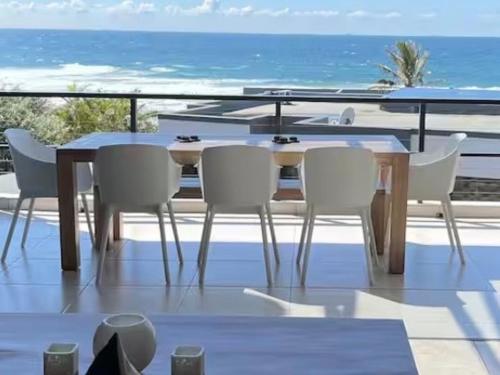 a table and chairs on a balcony with the ocean at 3 Bedroom - Salt Rock Beach Pad in Ballito