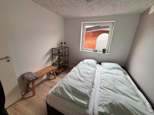 ein kleines Schlafzimmer mit einem Bett und einem Fenster in der Unterkunft Ribevej 12 in Egebæk