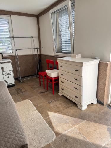 ein Schlafzimmer mit einer weißen Kommode und roten Stühlen in der Unterkunft Vila Aura in Podgorica