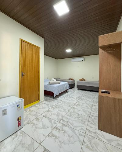 a large room with two beds and a door at Suítes no centro de Bonito, Bonito Brasil Turismo in Bonito