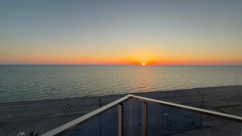 a sunset over the ocean on a pier at Pano Hotel in Gonio