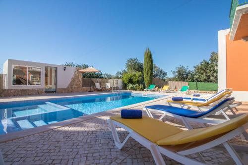 a swimming pool with two lounge chairs and a house at Quinta das Yuccas by Algarve Holidays in Boliqueime