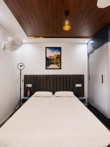 a bedroom with a large white bed with a wooden ceiling at RK Homes in Delhi