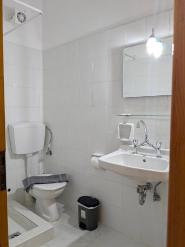 a white bathroom with a toilet and a sink at Two Brothers Parga in Parga