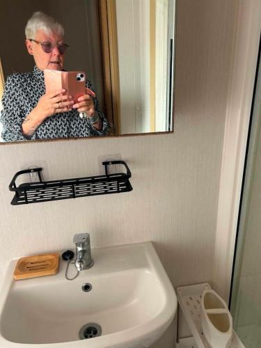 a woman taking a picture of herself in a bathroom mirror at The Pointon-Bordeaux Caravan Co in Rhyl