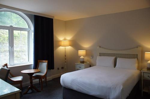 ein Schlafzimmer mit einem Bett, einem Tisch und einem Fenster in der Unterkunft WatersEdge Hotel in Cobh