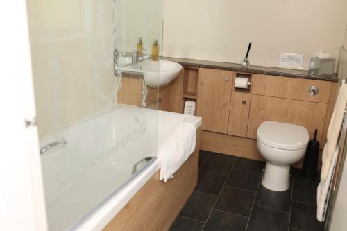 a bathroom with a tub and a toilet and a sink at Westlea Cottage in Turriff