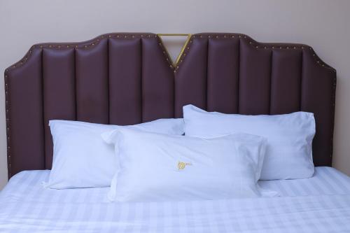 a bed with white pillows and a brown headboard at BUDDIEZ hotel limited in Kampala
