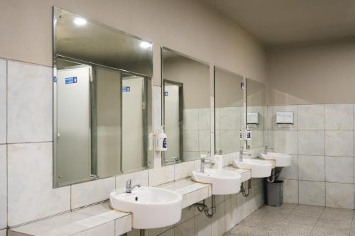 a public bathroom with three sinks and mirrors at HeHa Waterfall Suites & Camping Ground in Paragajen