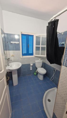 a blue tiled bathroom with a toilet and a sink at Menzel Rayan in Midoun