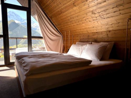 a bed in a room with a large window at Mtaura Cabins in Kazbegi