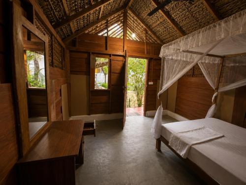 a room with two beds and a table and windows at once more hostel in Pottuvil