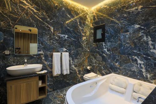 a bathroom with a tub and a sink and a bath tub at Farida Palace Hotel in Al Aqālitah