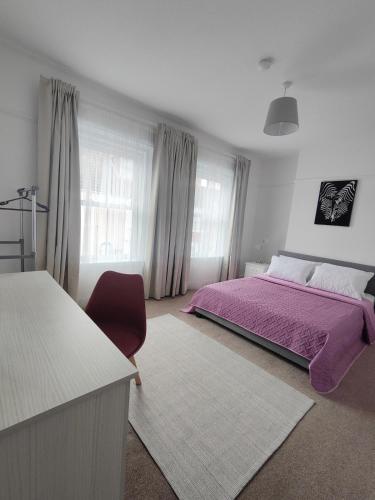 a bedroom with a purple bed and a red chair at Sand Castle in Weymouth