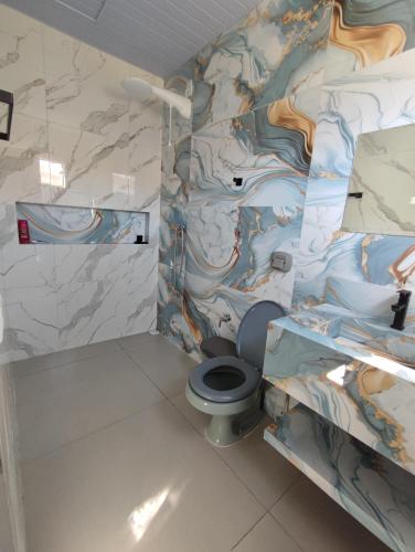 a bathroom with a toilet with a painting on the wall at Quarto Califórnia in Campo Novo do Parecis