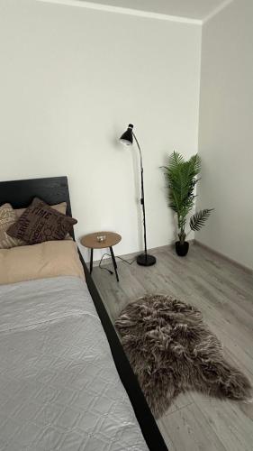 a bedroom with a bed and a table and a plant at Bright Apartment with Forest View Balcony in Naujoji Akmenė