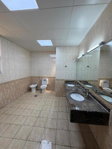 a large bathroom with two sinks and two toilets at Iman Guest House in Al Qurayyah