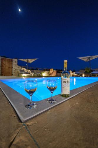 a bottle of wine and two wine glasses next to a swimming pool at Stavlos Villa - Private Pool in episkopi-heraklion