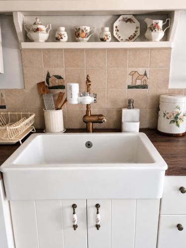 a white sink in a kitchen with dishes on a shelf at Stellinas Pretty House in Andros