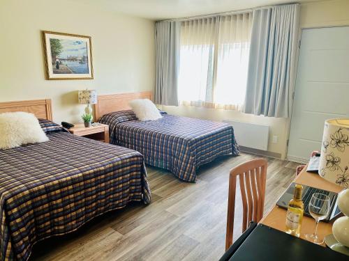 a hotel room with two beds and a table at Auberge Cap Martin in La Pocatiere